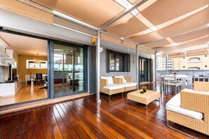 Un interior moderno con piso de madera, un conjunto de sofás, un comedor y una cocina visible a través de puertas de vidrio.