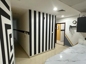 A hotel room with a curved marble bed, a striped wall, a door leading to another room, and a clock on the wall. - City Stay Partition Room in Al Barsha1 (Dubai)