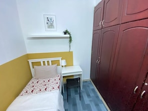 Een slaapkamer met een bed, een bureau, een stoel en een kledingkast.