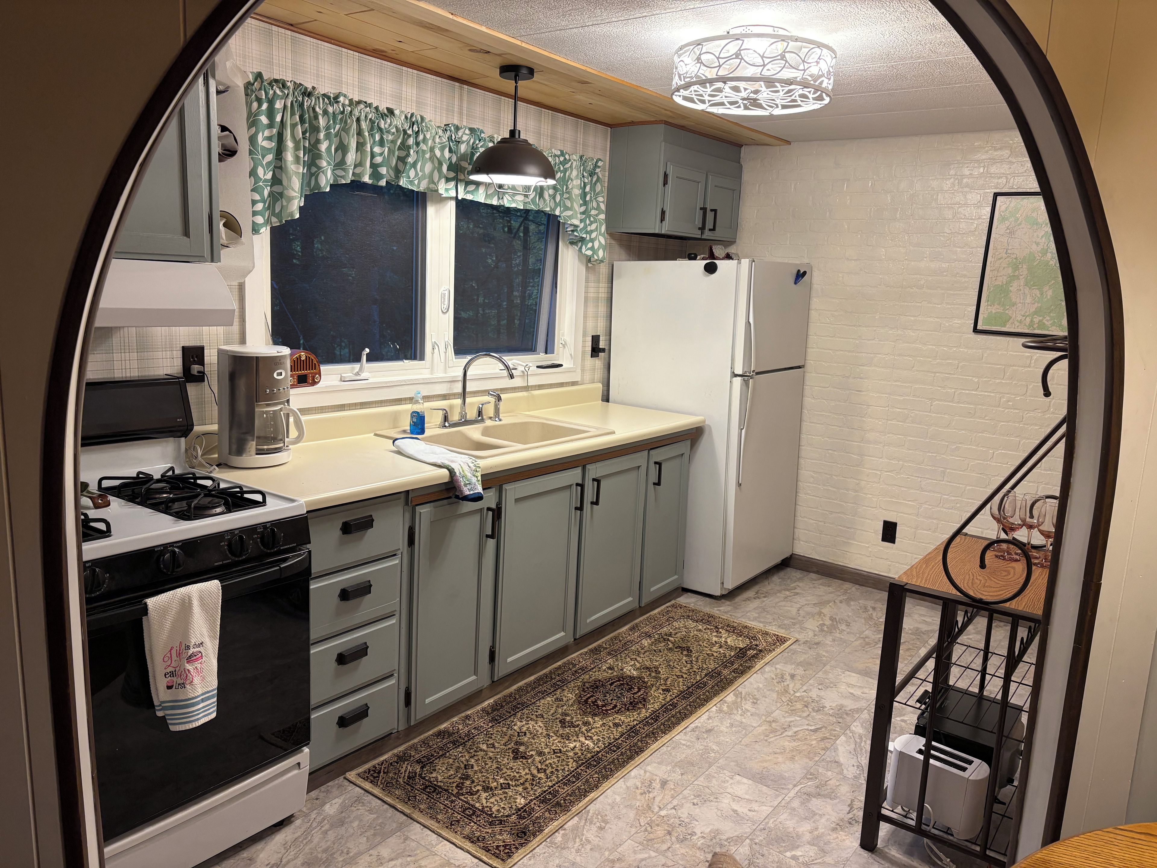A compact kitchen with a gas stove, a sink, a refrigerator, and a microwave.