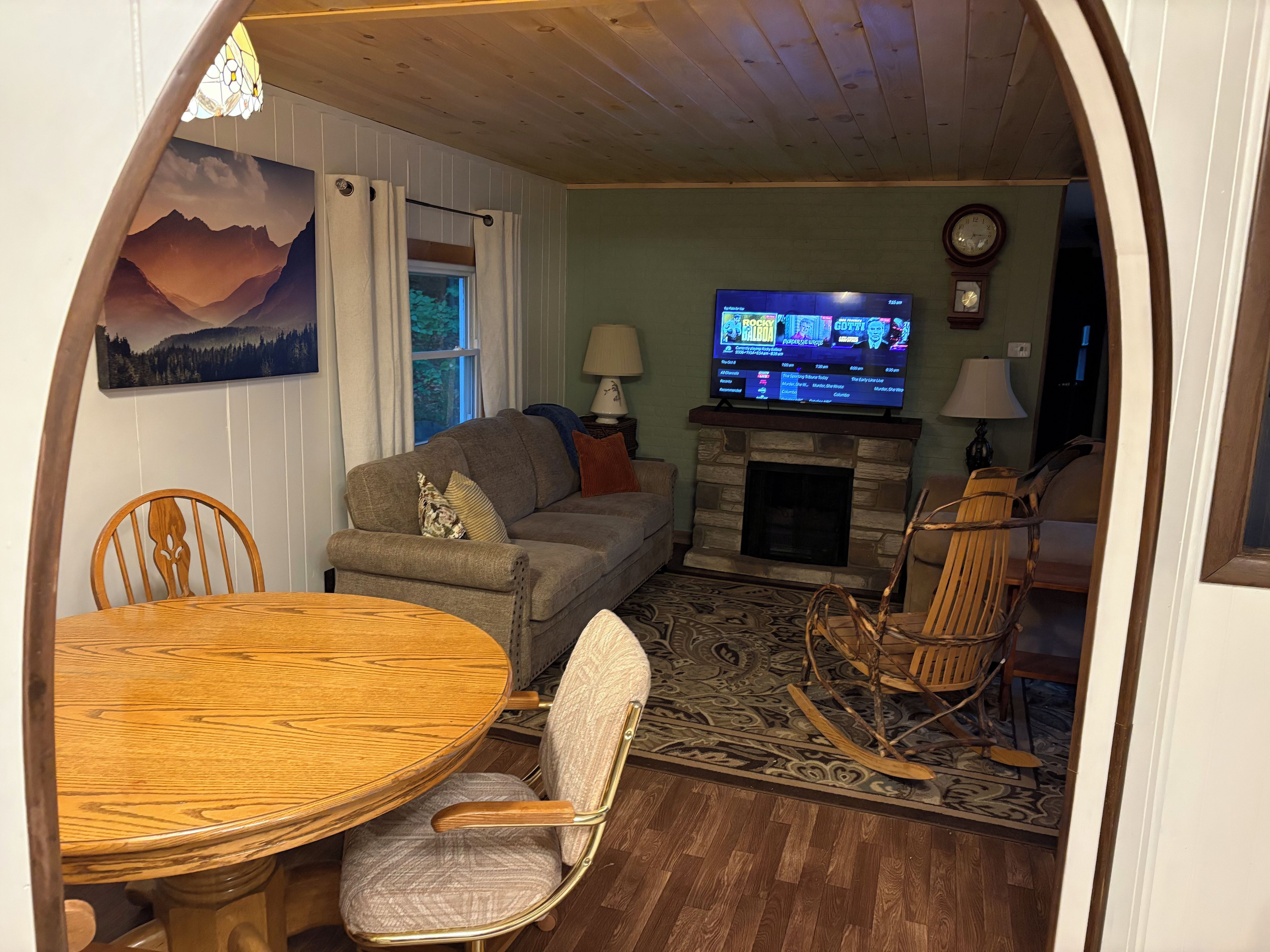 Een knusse woonkamer met een open haard, een televisie en een eethoek met een tafel en stoelen.