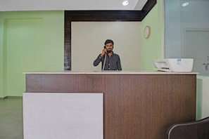 Un mostrador de recepción con un reloj en la pared y una impresora en el mostrador.