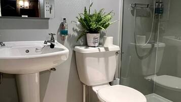 A modern bathroom with a white sink, toilet, and glass-enclosed shower.