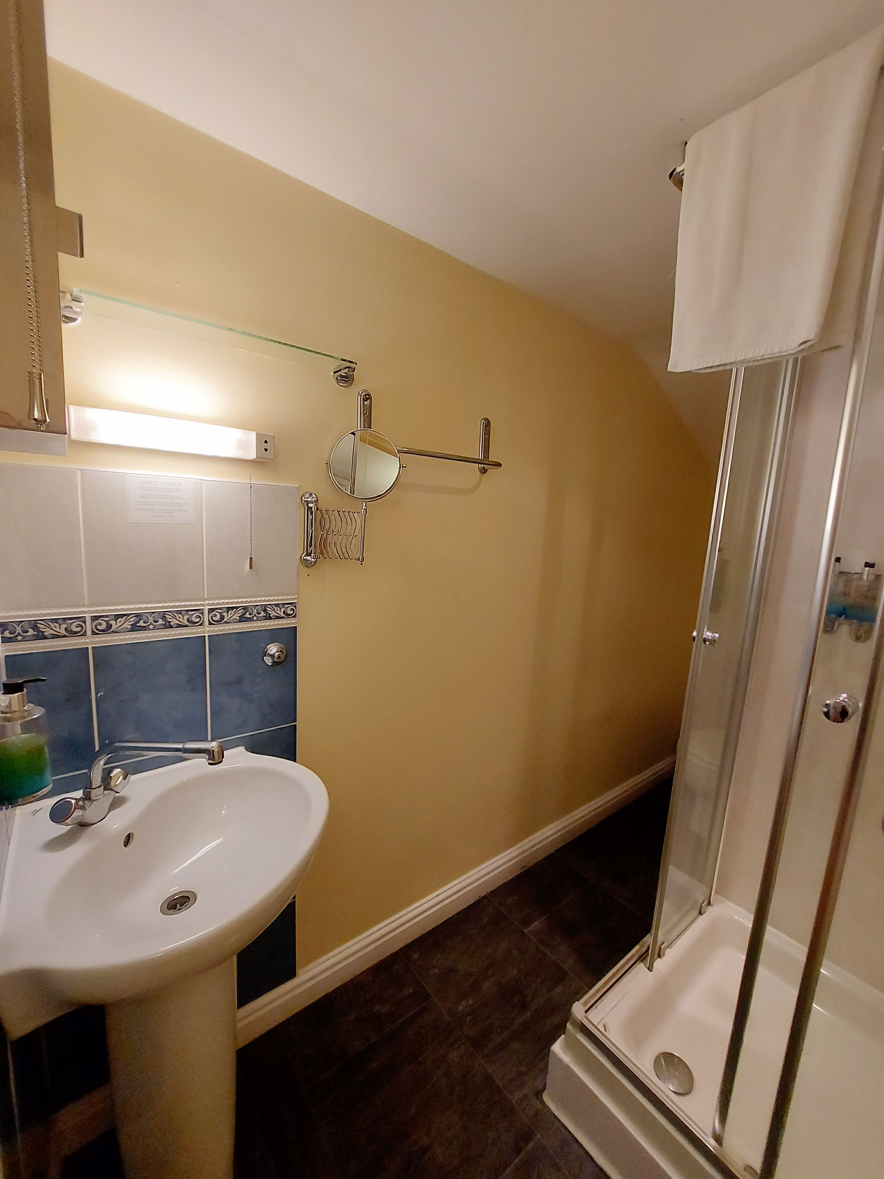 A bathroom with a sink, mirror, towel rack, and shower.