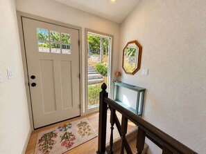 A hallway with a door, a mirror, and a console table. - The Sunny Perch - Lakefront Home (Osage Beach)
