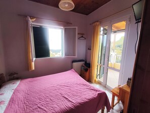 A bedroom with a bed, a window, a radiator, and a small table. - Tranquil 2-Bed Village Haven in Episkepsi - Ideal Long-Stay Retreat (Episkepsi)