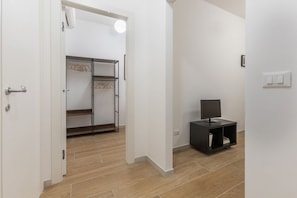A room with a wardrobe, a television on a stand, and a light switch on the wall. - GuestHost - Le Due Torri Apartment with a courtyard! (Bologna)