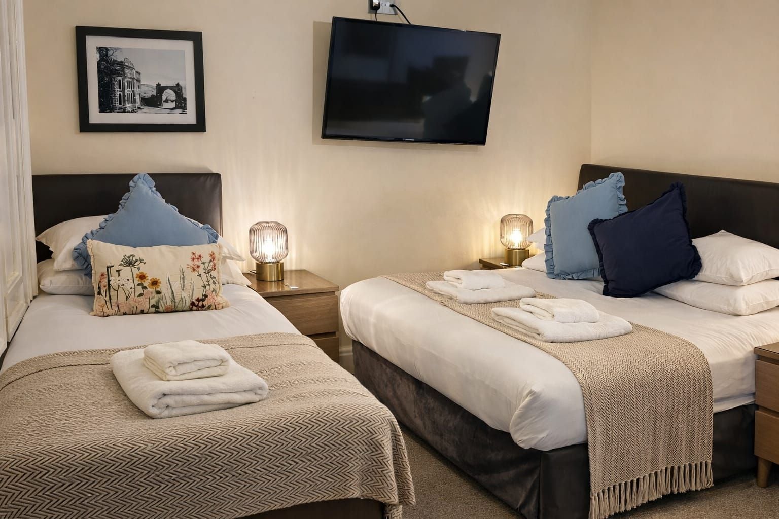 A hotel room with two beds, a television, and a framed picture on the wall.
