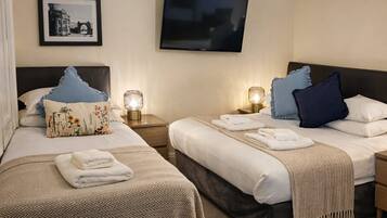 A hotel room with two beds, a television, and a framed picture on the wall.