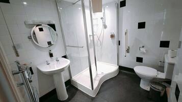A modern bathroom with a glass-enclosed shower, a white sink, and a toilet.