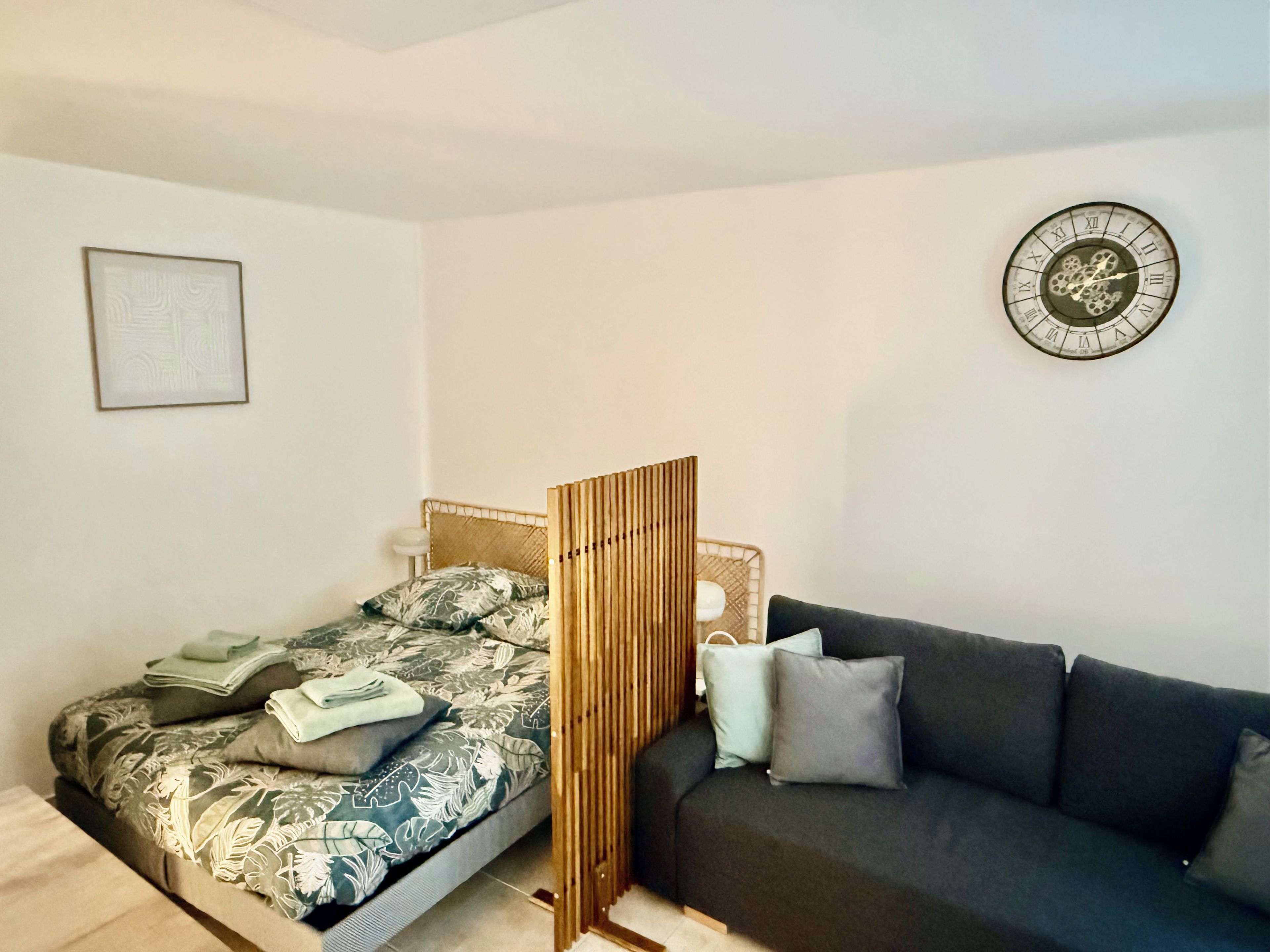 Una camera da letto con un letto, un comodino, una sveglia a muro e un divano.