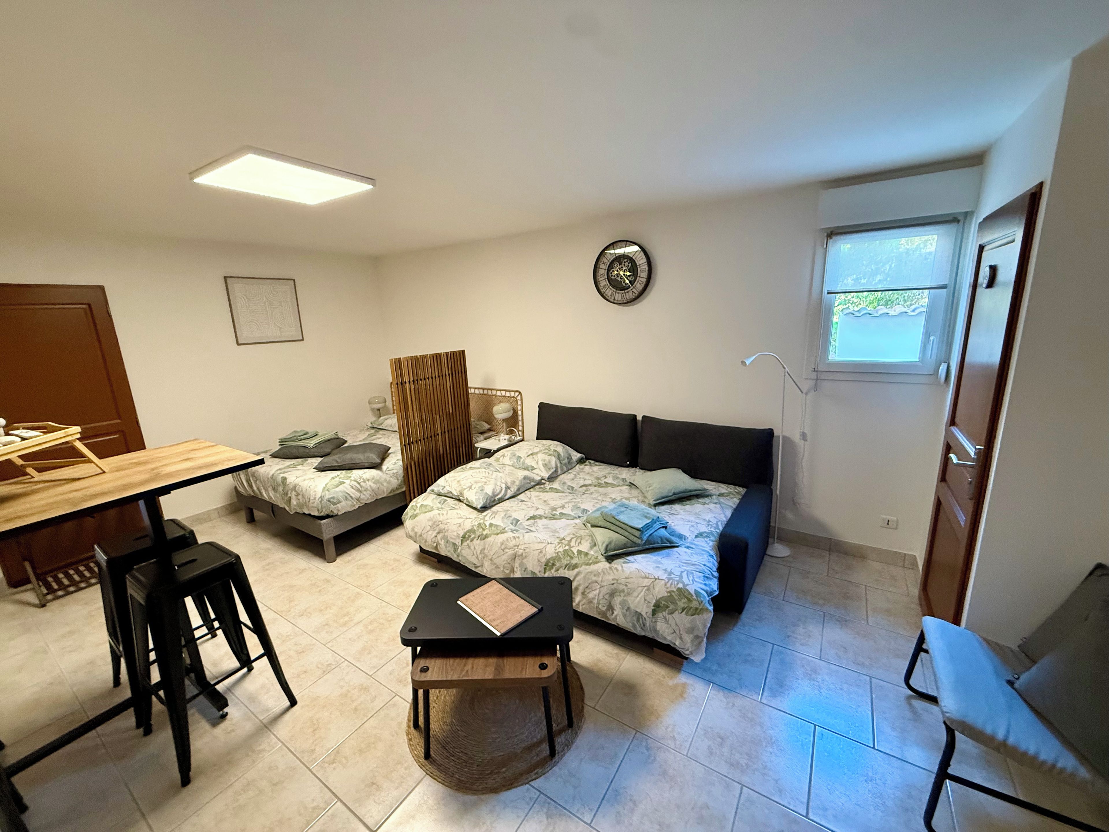 A compact room with a bed, a small table, a chair, and a desk.