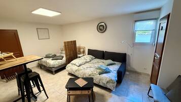 A compact room with a bed, a small table, a chair, and a desk.