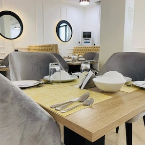 Un comedor con una mesa de madera, sillas tapizadas en gris y un espejo redondo en la pared.