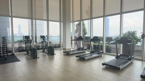 A gym with treadmills, weight machines, and a view of the cityscape through large windows. - Skyline Service Suite KLCC at Platinum (Kuala Lumpur)