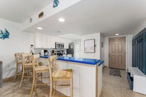 Una cocina moderna con armarios blancos, encimera azul y sillas de madera.