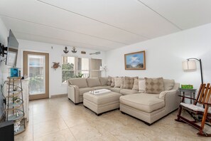 Una sala de estar con un sofá modular, una mesa de centro, un televisor y una estantería.