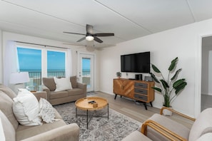 Ein modernes Wohnzimmer mit Sofa, Couchtisch, Fernseher und einem Balkon mit Blick.