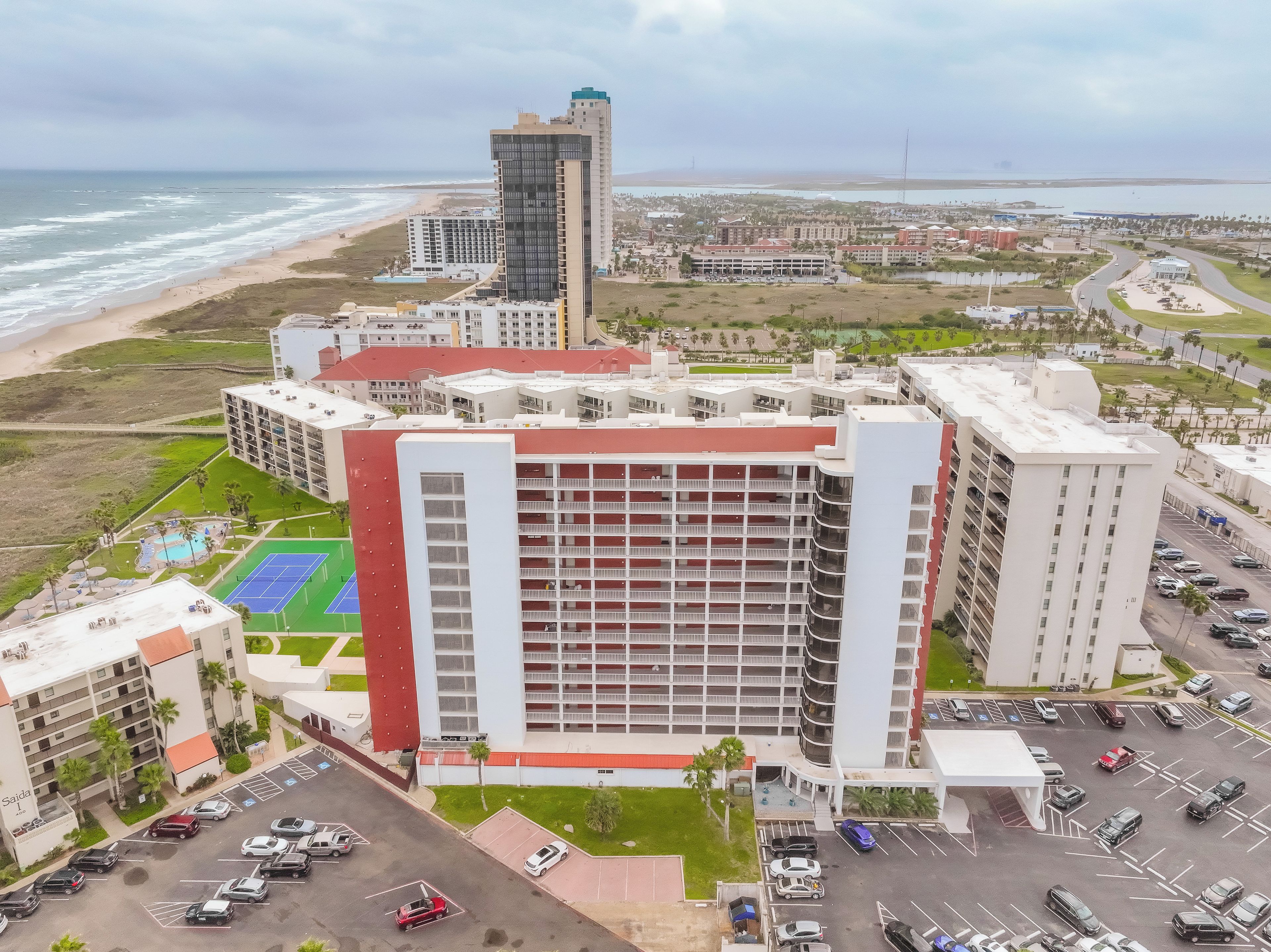 A multi-story hotel with a rooftop pool and a parking lot.