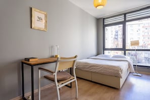 A bedroom with a bed, a desk, and a chair. There is a window with a view of buildings outside. - Fabulous Large Duplex - 3 Bedroom 2 Bathroom - Terrace - Fast WiFi - Full Aircon (Şişli)