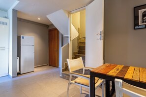 A kitchen with a refrigerator, a dining table with chairs, and a staircase leading to an upper level. - Fabulous Large Duplex - 3 Bedroom 2 Bathroom - Terrace - Fast WiFi - Full Aircon (Şişli)