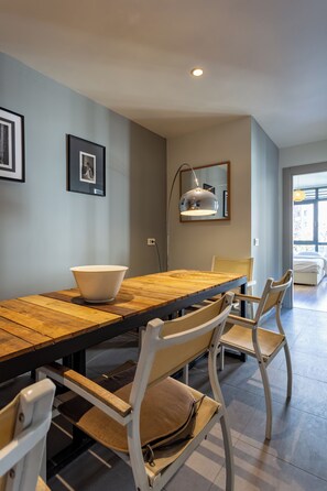 A dining area with a wooden table, white chairs, a bowl, and a pendant light. - Fabulous Large Duplex - 3 Bedroom 2 Bathroom - Terrace - Fast WiFi - Full Aircon (Şişli)