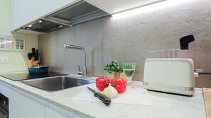 A kitchen with a stainless steel sink, a white toaster, and fresh vegetables on the counter. - Italianway Comfort - Soperga 15 (Milan)