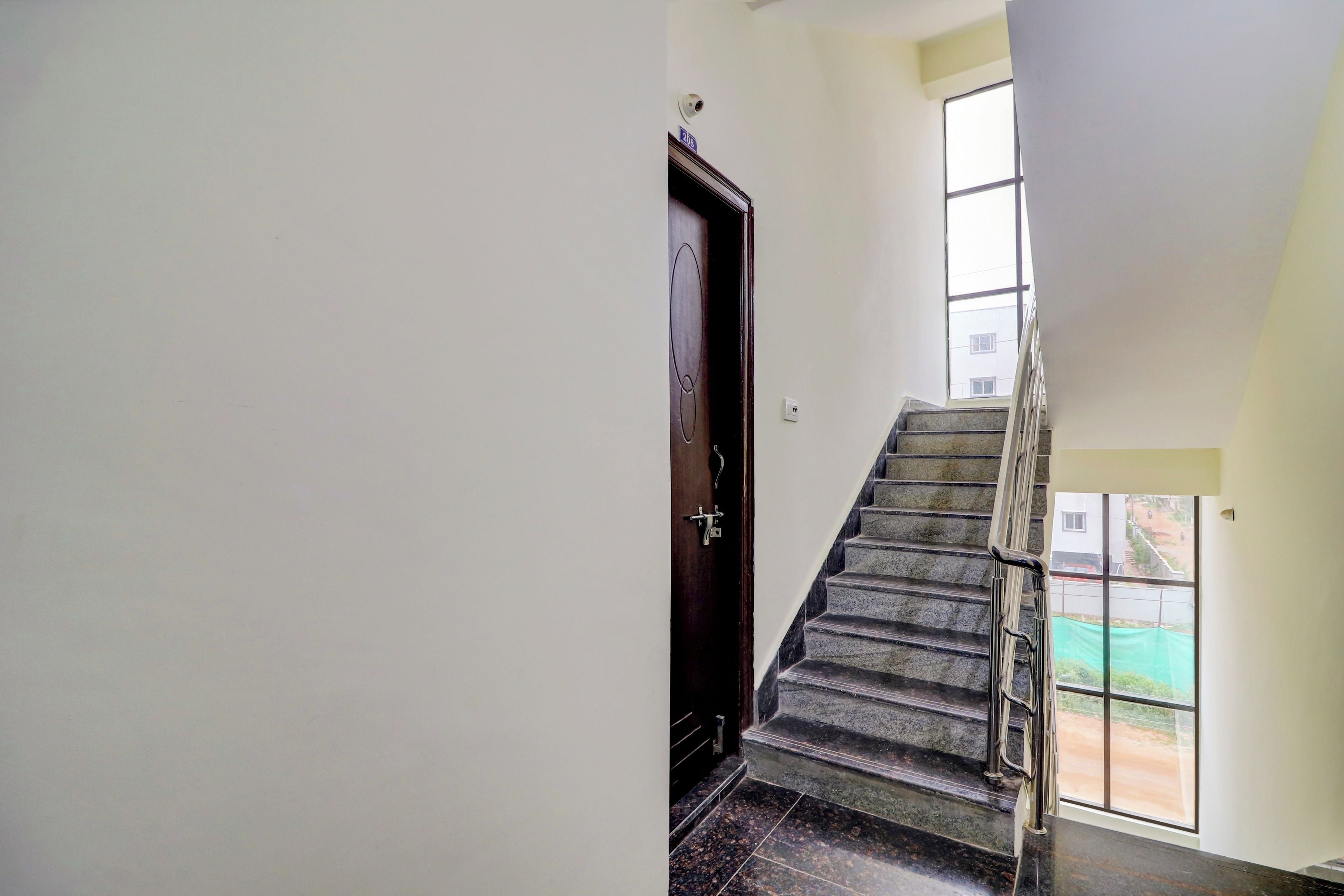 Una escalera con barandilla de metal que lleva a un rellano con una puerta.