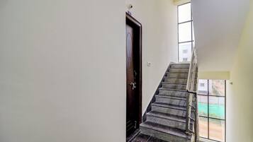 Una escalera con barandilla de metal que lleva a un rellano con una puerta.