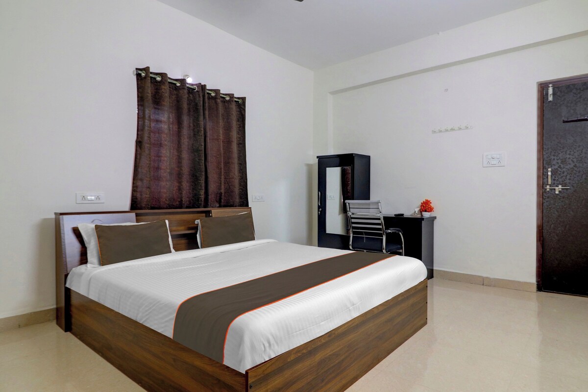 Una habitación de hotel con cama, escritorio, silla, armario y puerta.
