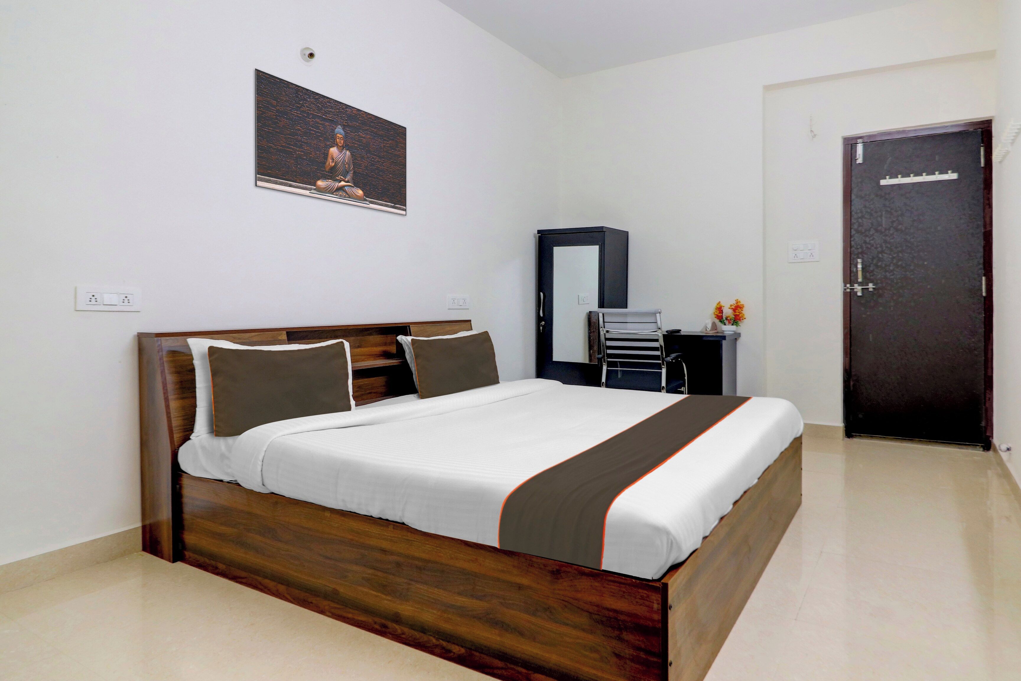 Un dormitorio con una cama de madera, una mesita de noche, un espejo y una puerta.