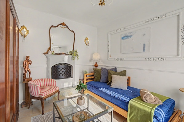 Una sala de estar con chimenea, un sofá, una silla y una mesa de centro de vidrio.