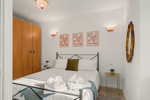 A bedroom with a bed, a wardrobe, a bedside table with a lamp, and wall-mounted lights.