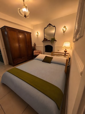Una camera da letto con un letto grande, un armadio in legno, una sedia, un camino e applique.