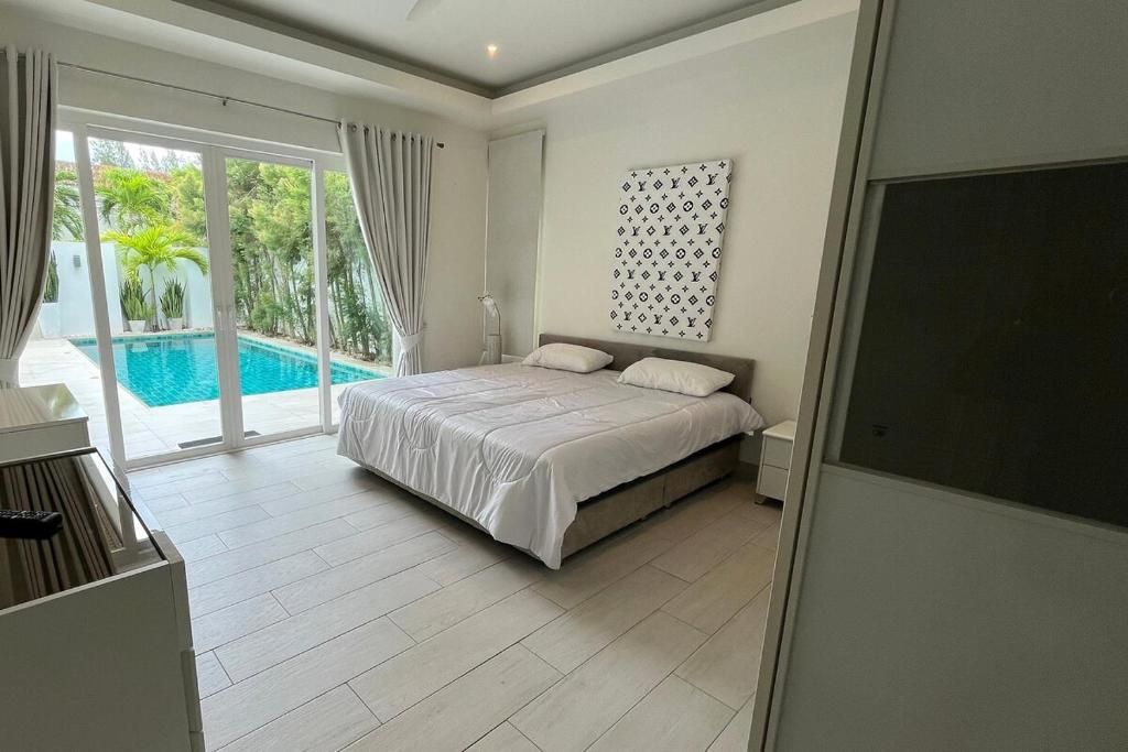 A bedroom with a bed, a large window, and a view of a swimming pool.