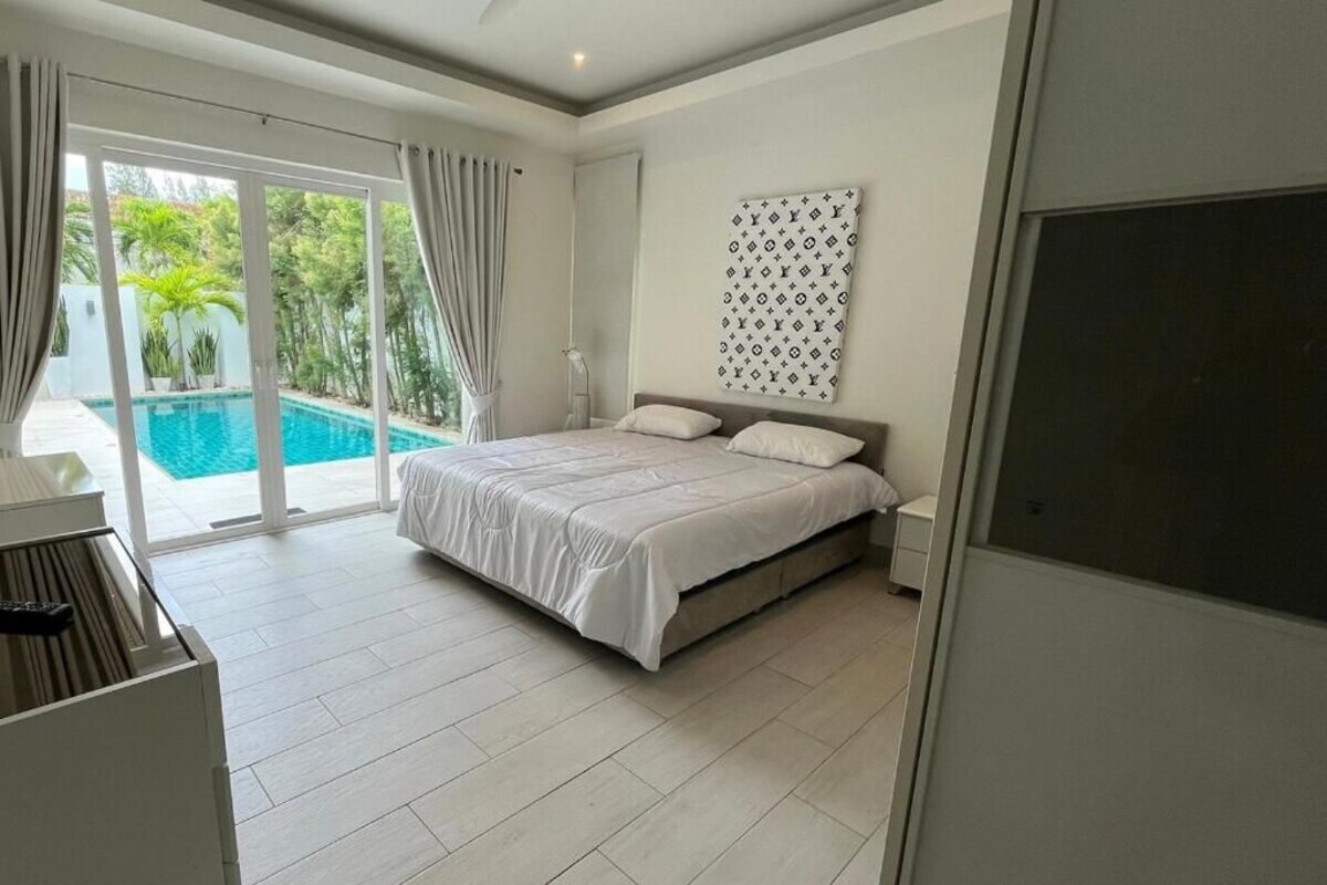 A bedroom with a bed, a large window, and a view of a swimming pool.