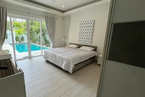 A bedroom with a bed, a large window, and a view of a swimming pool. - Orchid Paradise Homes OPV505 (Hua Hin)