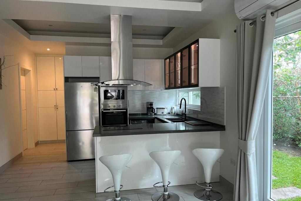 A modern kitchen with a central island, stainless steel appliances, and a large window.