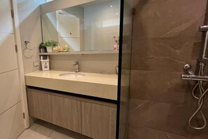 A modern bathroom with a sink, mirror, and shower. - Orchid Paradise Homes OPV505 (Hua Hin)