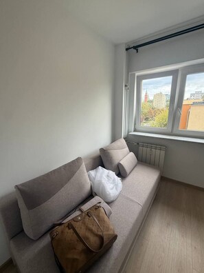 A room with a grey sofa, a white pillow, and a brown bag. - Lumina 2BR Apt w/ Balcony near Center (Warszawa)