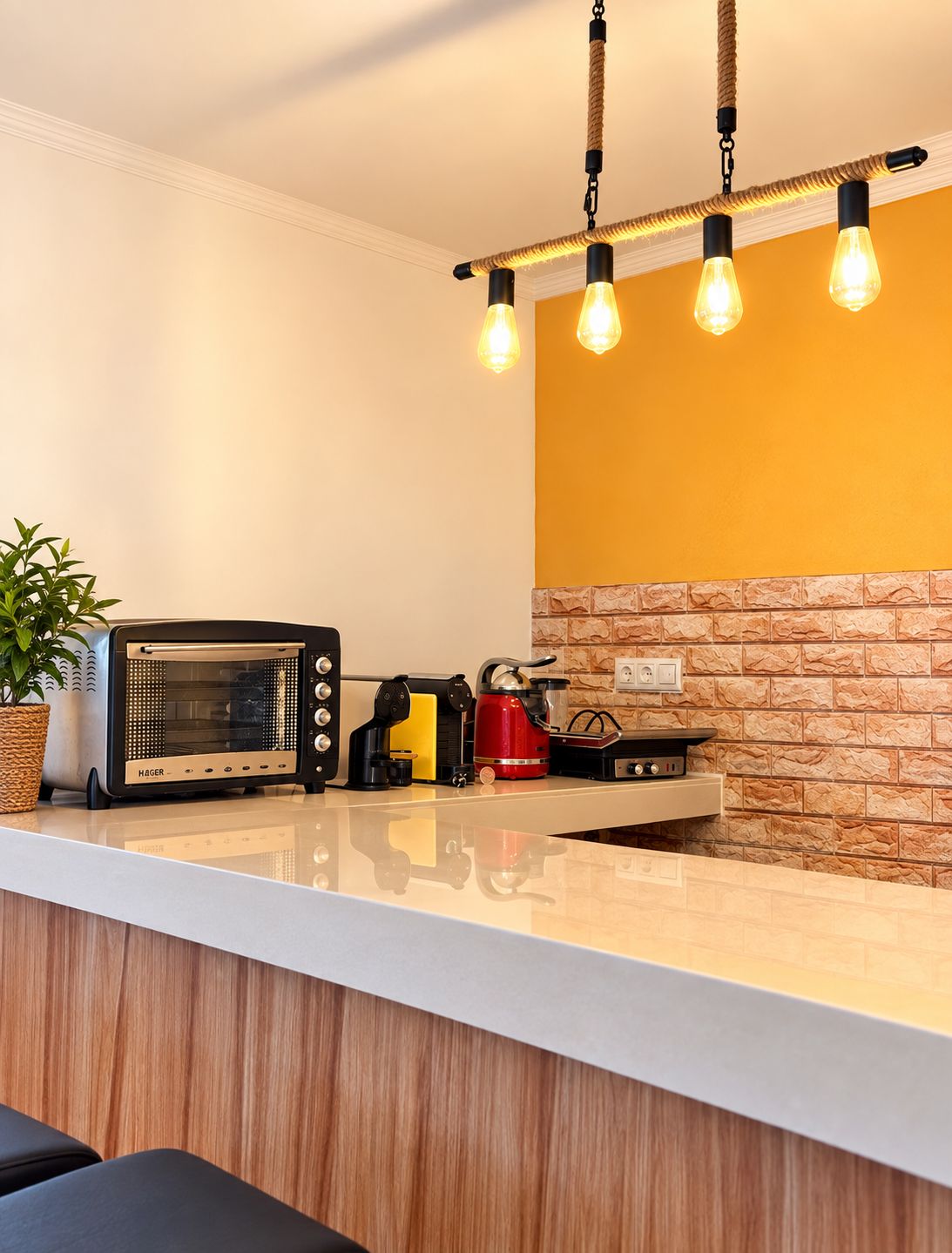 Une cuisine au design moderne, avec un plan de travail blanc, une cuisinière encastrée, une bouilloire rouge et une radio d’époque.