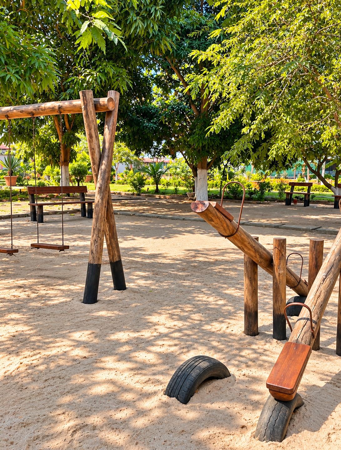 A playground with swings and tire swings, surrounded by trees and potted plants.