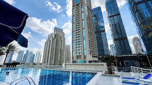 A modern high-rise building with a swimming pool in the foreground. - Sleek 1BHK , Dubai Marina (Dubai)