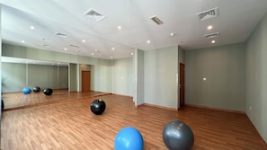 A gym with exercise balls, wooden flooring, and mirrors on the walls. - Sleek 1BHK , Dubai Marina (Dubai)