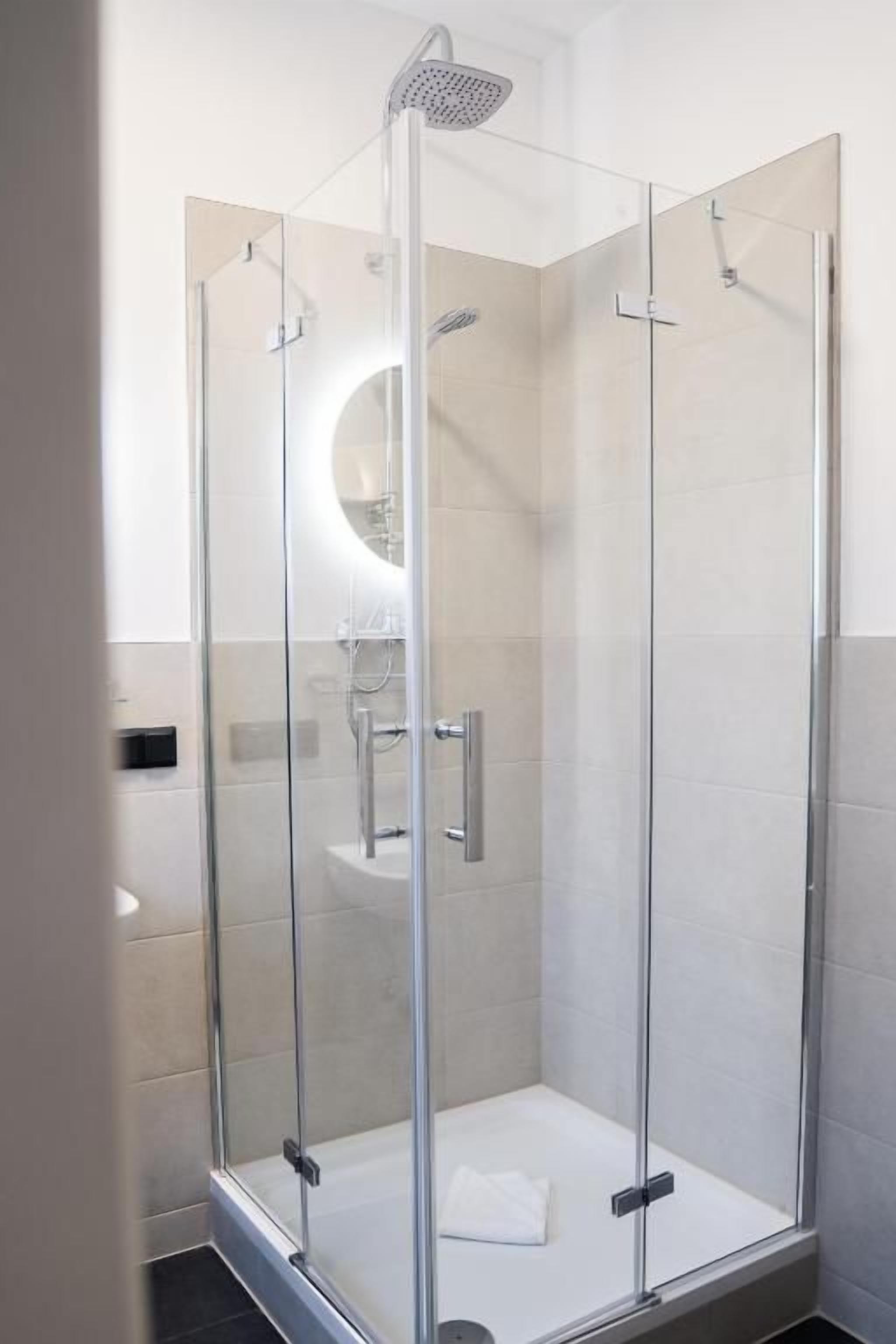 Eine Duschkabine mit Handbrause und am Wand montiertem Wasserhahn.