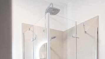 Eine Duschkabine mit Handbrause und am Wand montiertem Wasserhahn.