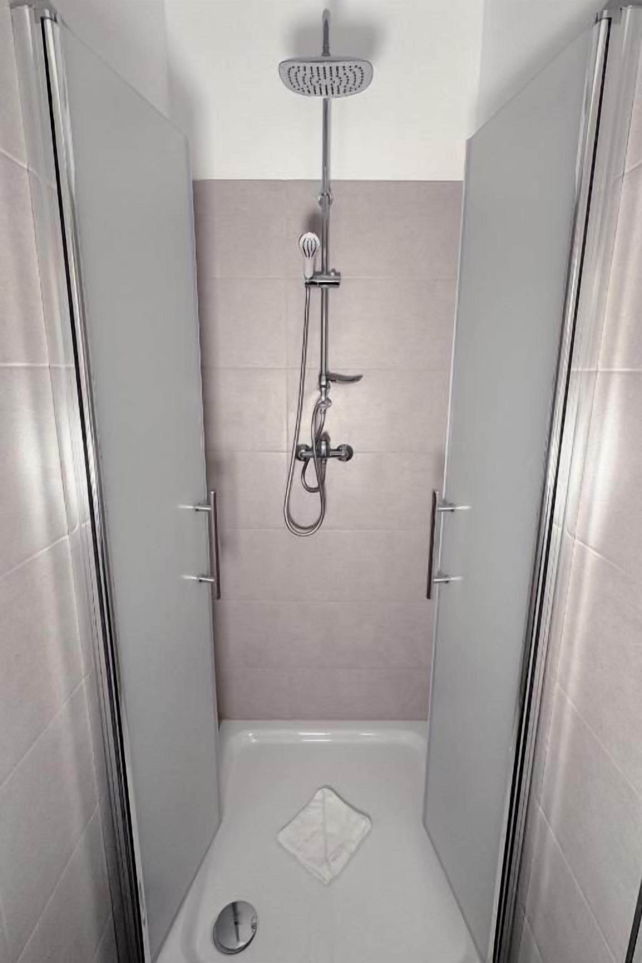 Eine begehbare Dusche mit drei Handbrausen.