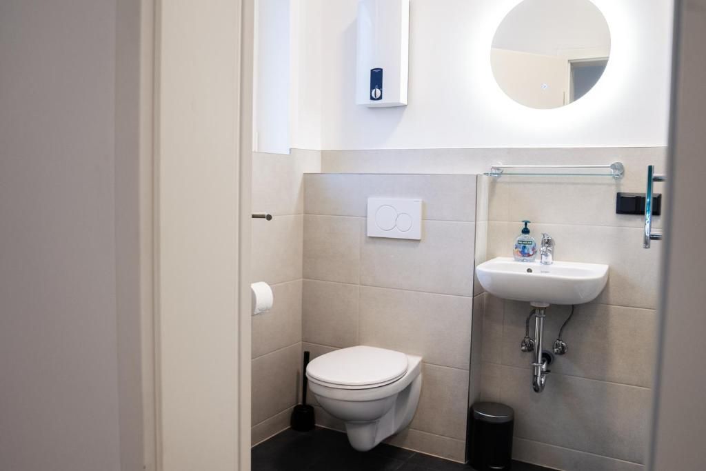 A modern bathroom with a toilet, sink, and mirror.