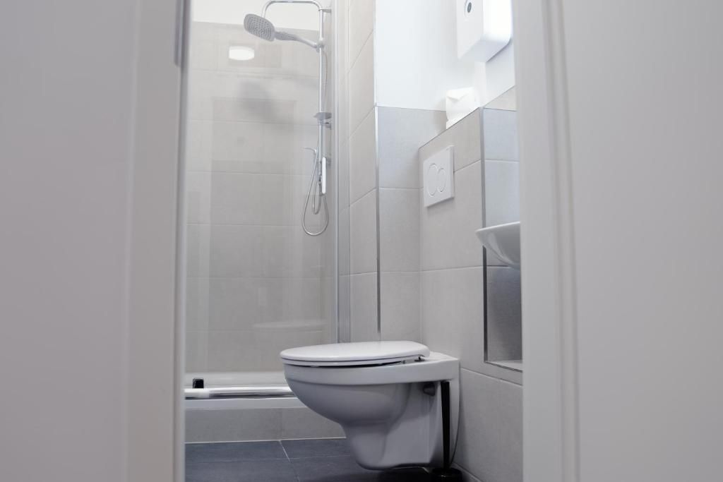 A modern bathroom with a toilet, shower, and a towel rack.