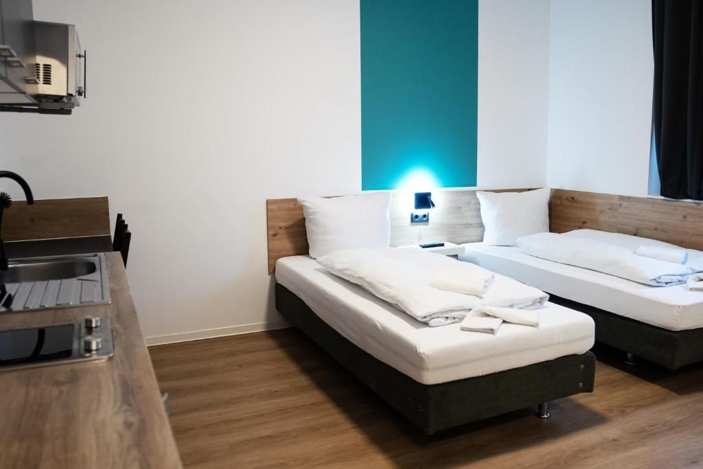 Habitación de hotel con dos camas, un escritorio de madera y una pared azul decorativa.